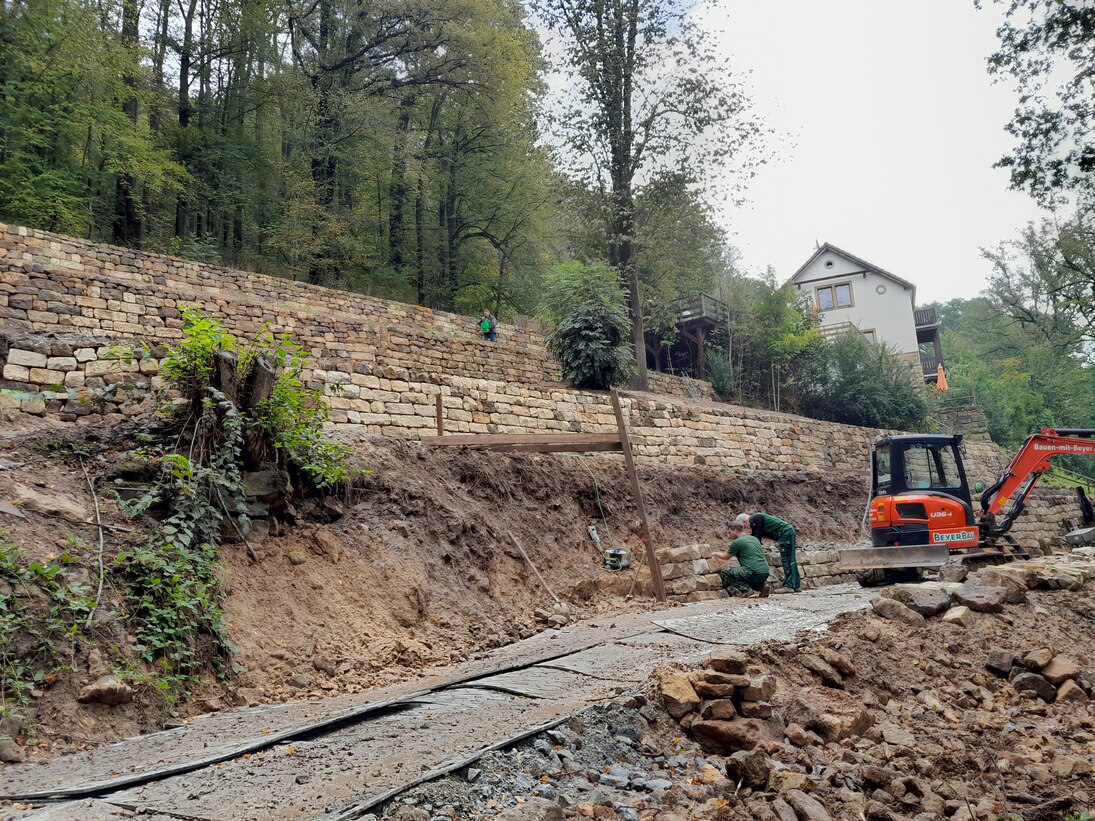 Baumaßnahmen an einer Trockenmauer im schwierigen Gelände am Hang.